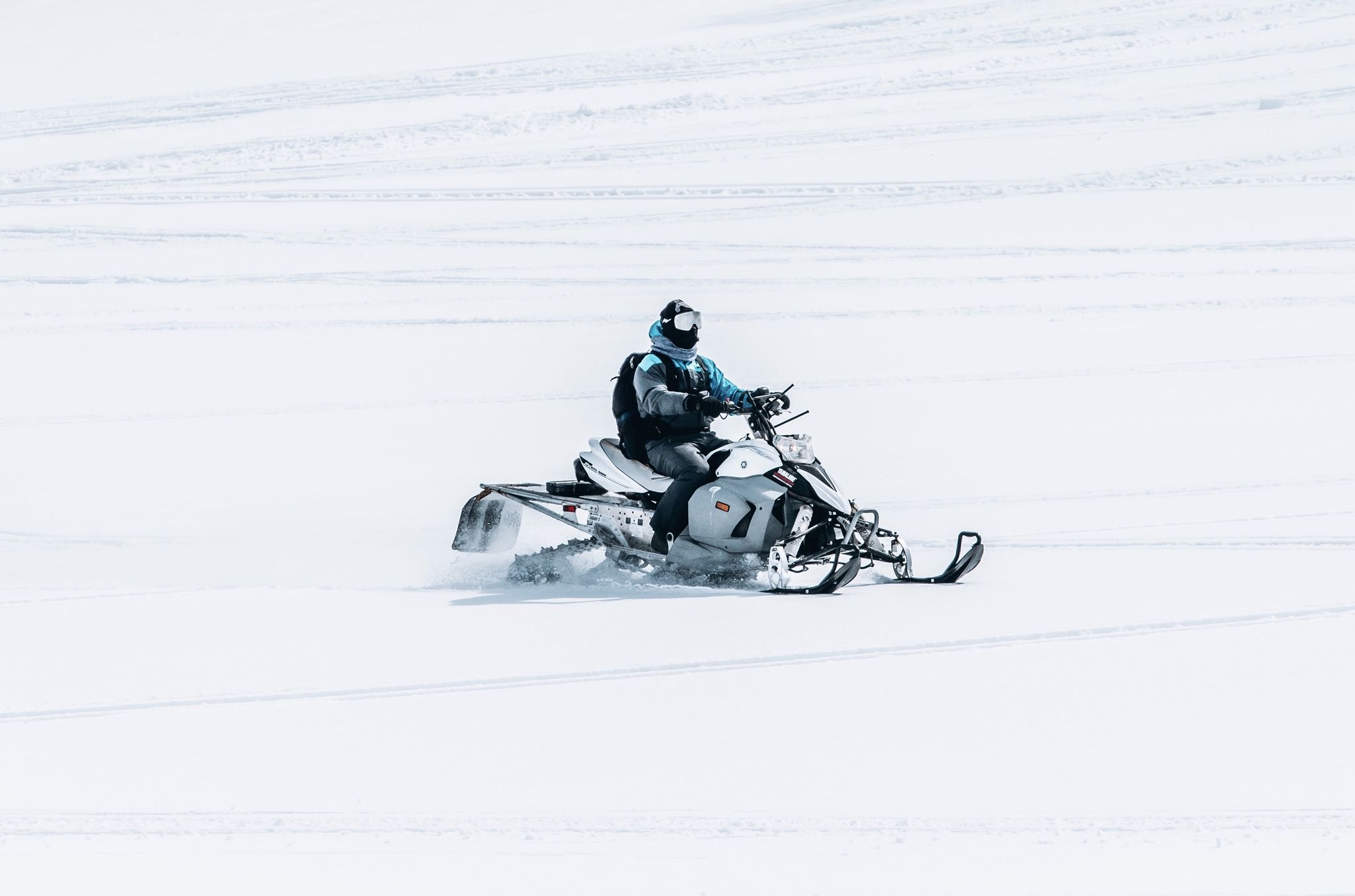 Un homme pilotant une motoneige dans un grand champ enneigé